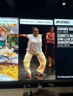 A Black woman wearing yellow pants dances on a promo billboard