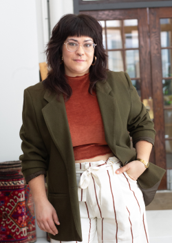 a picture of a white woman in an olive green blazer and white striped pants