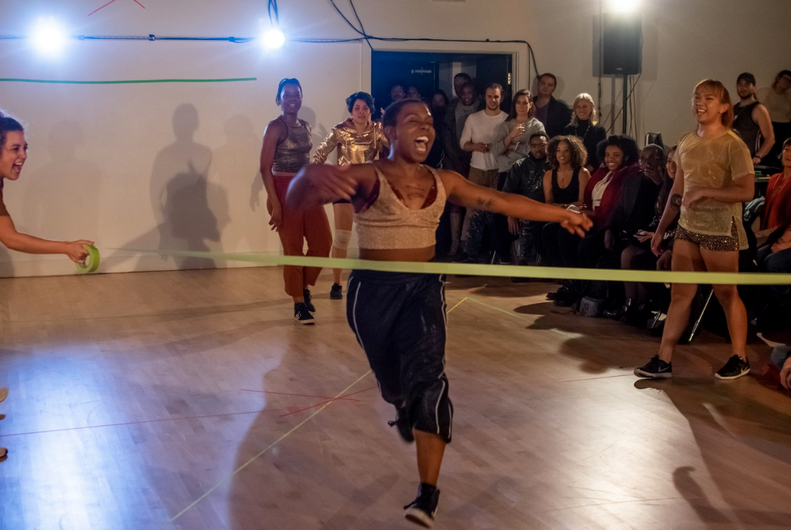 a fierce performer crosses what looks like a finish line with people cheering