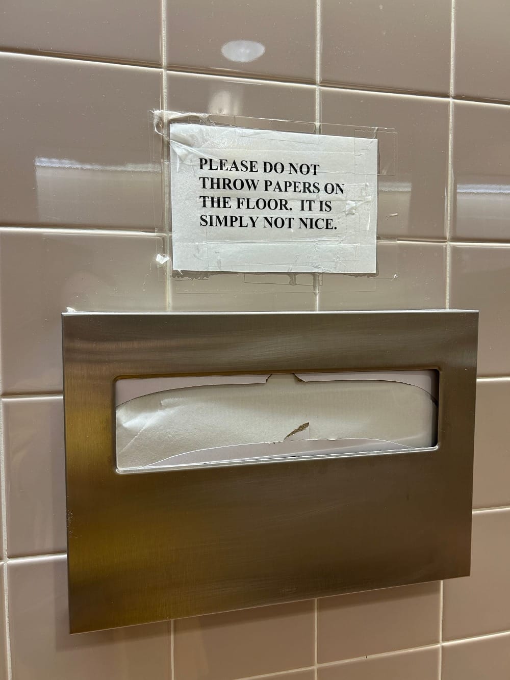 restroom sign reads: please do not throw papers on the floor. it is simply not nice.